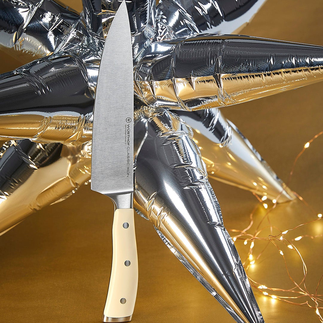 Knife with a beige handle on a reflective gold and silver background