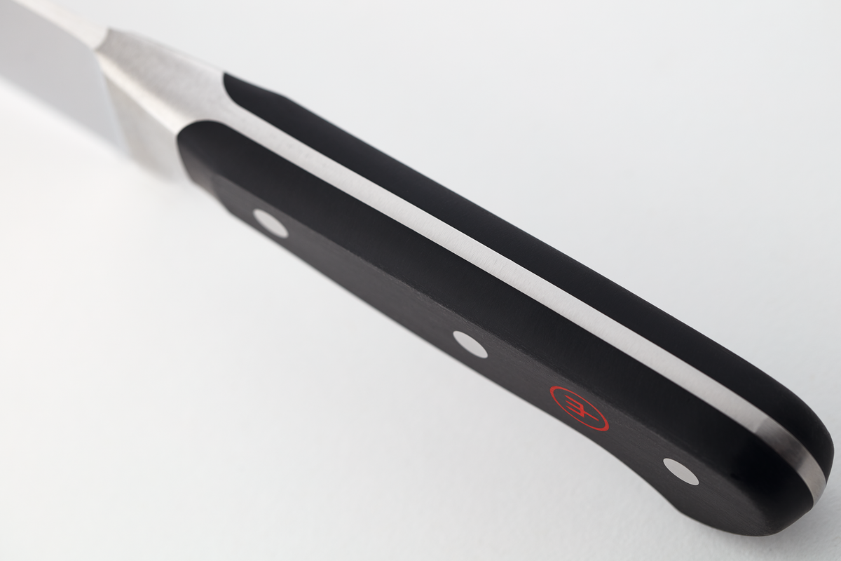 Close-up of a black kitchen knife handle with three metal rivets and a red circular logo on a smooth matte surface next to a polished steel tang.