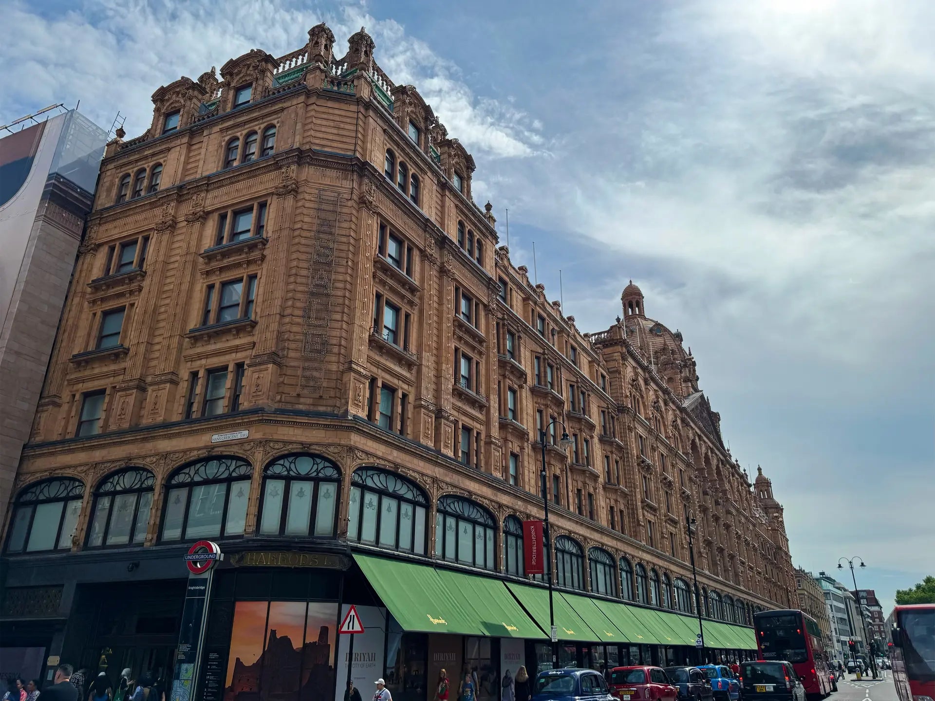 Large ornate building with a green awning on a city street