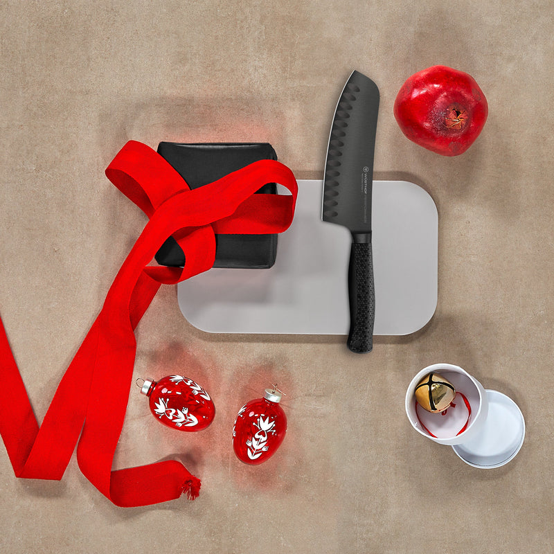Knife, cutting board, red ribbon, and decorative items on a beige surface